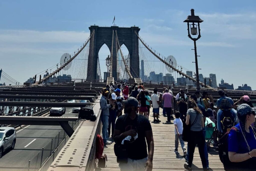 pessoas atravessando a ponte do brookyn em dia de sol- foto autoral