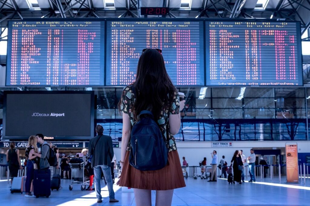 mulher olhando o painel de vôos no aeroporto