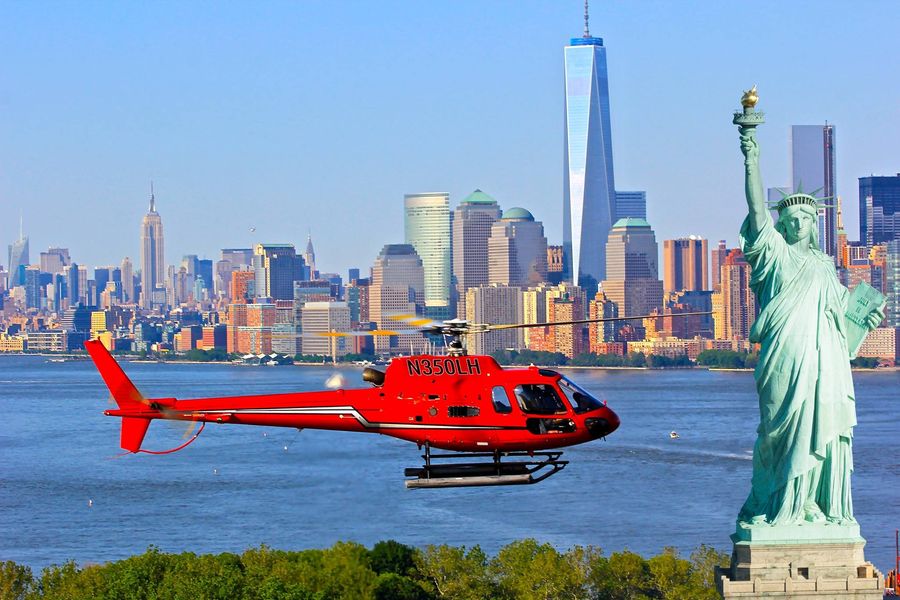 helicóptero próximo a estátua da liberdade e manhattan ao fundo