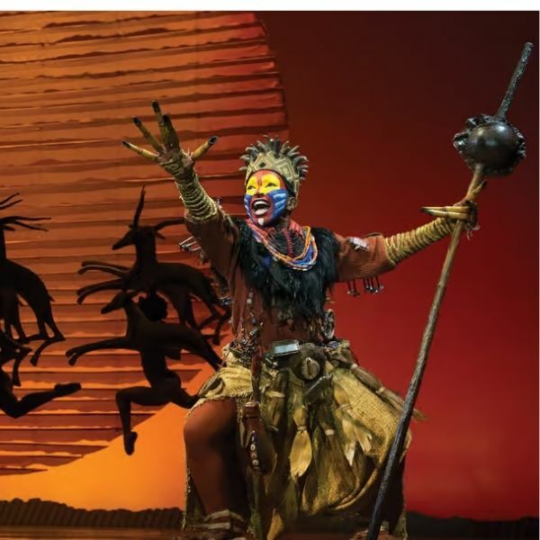 Cena do musical O Rei Leão da Broadway, mostrando os figurinos elaborados e a produção visual deslumbrante que caracteriza este musical da Broadway