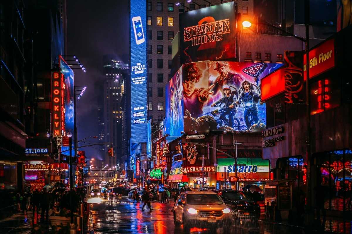 Vista noturna dos teatros iluminados da Broadway em Times Square, Nova York, mostrando os letreiros coloridos dos musicais da Broadway