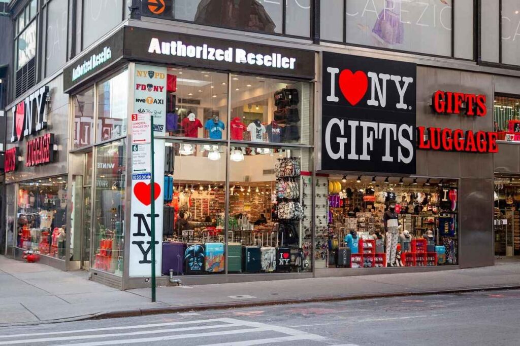 Souvenirs from New York City, capturing the vibrant energy and iconic landmarks of the Big Apple. In the foreground, an assortment of classic NYC memorabilia - keychains, magnets, and miniature Statue of Liberty figurines. The middle ground showcases a selection of artisanal, handcrafted items, such as custom-designed t-shirts, tote bags, and local artisan jewelry. In the background, the stunning skyline of Manhattan with the Empire State Building and other skyscrapers, bathed in a warm, golden-hour glow. The overall scene exudes a sense of excitement and inspiration, inviting the viewer to discover the unique and authentic souvenirs that capture the essence of New York City. Loja de Sovenirs em Nova York