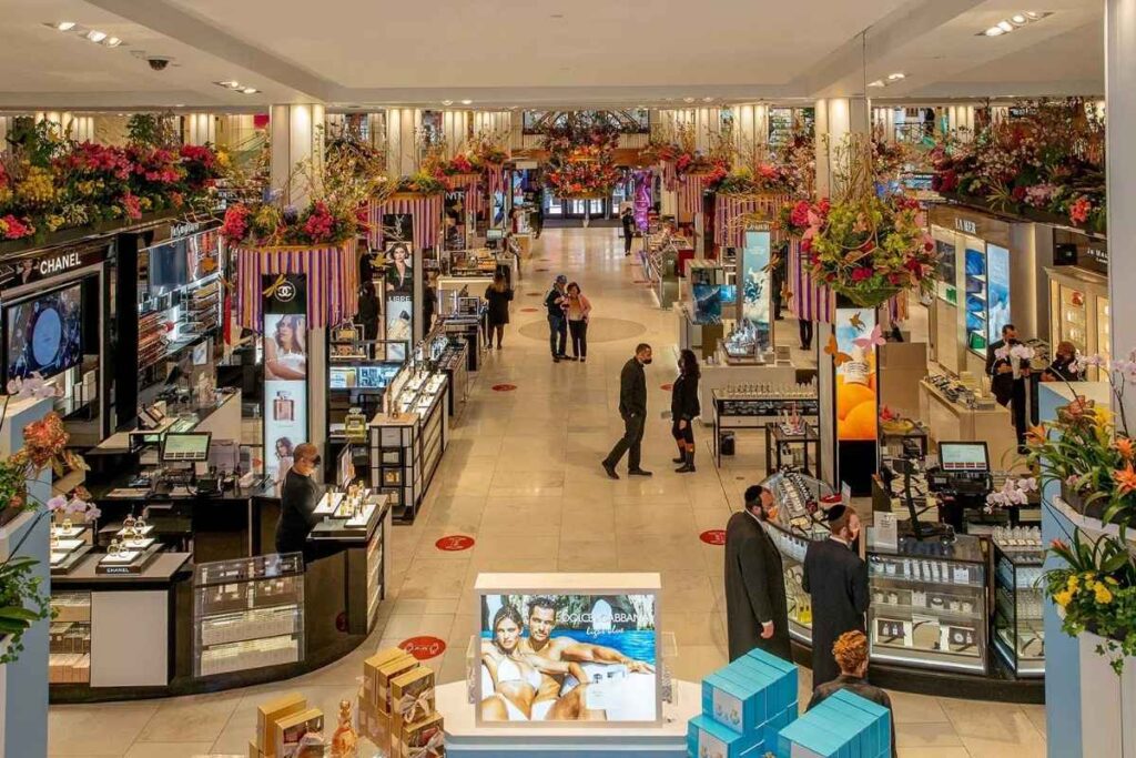 A vibrant, bustling department store interior with warm, inviting lighting. The foreground features an array of neatly organized merchandise, from clothing and accessories to home goods and electronics. The middle ground showcases elegant fixtures, grand staircases, and ornate architectural details that evoke the grandeur of a traditional department store. In the background, a panoramic view of the store's open floor plan, with customers browsing the aisles and cashiers assisting at the checkout counters. The overall atmosphere conveys a sense of excitement and opportunity, perfect for a shopping guide targeting Brazilian visitors to New York City. Compras na Macy's em Nova York