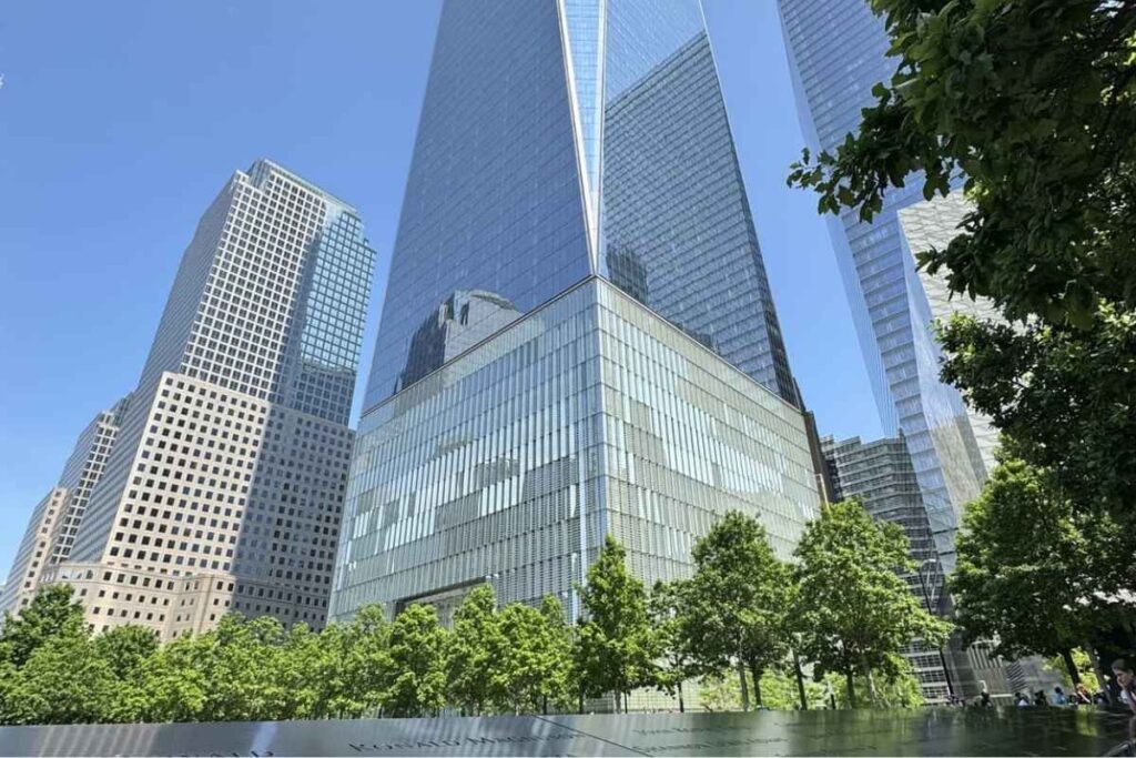One World Trade Center se erguendo com céu azul, visto da base da Piscina do Memorial 11/09, simbolizando a resiliência de Nova York, foto autoral.
