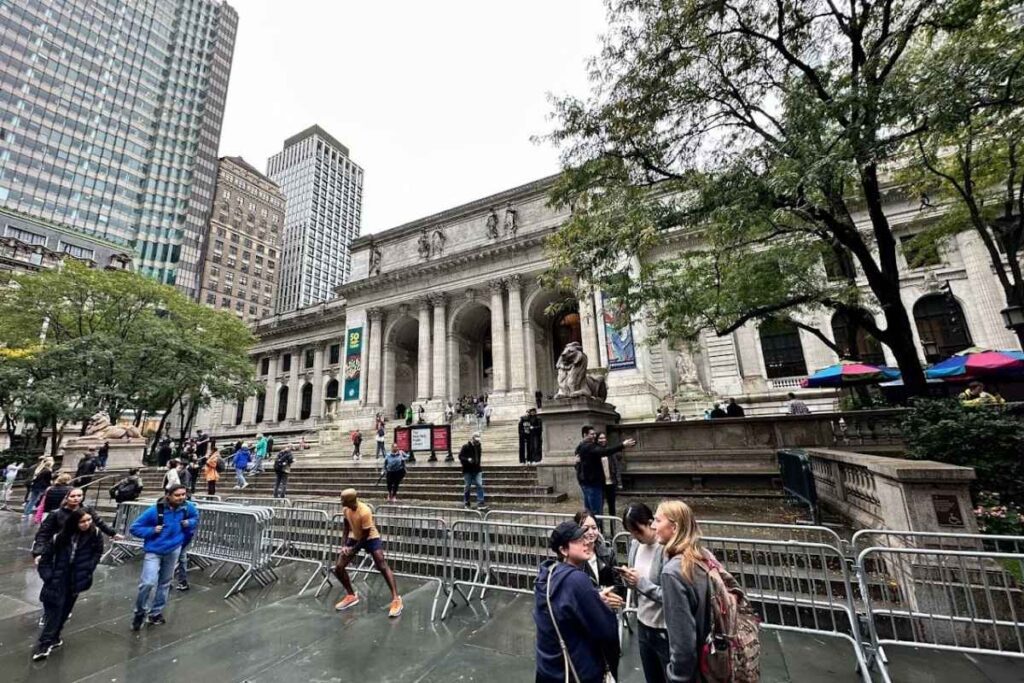 Biblioteca pública em Nova York com pessoas entrando, saindo e estudando ao redor do prédio em um dia ensolarado. foto autoral