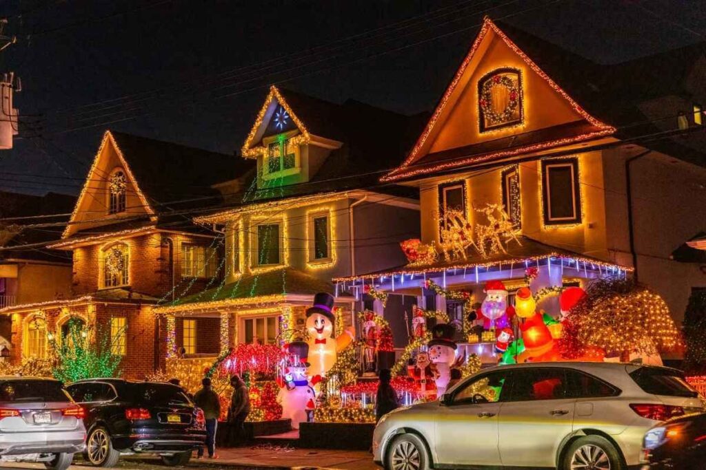 Rua residencial do Dyker Heights à noite, com casas decoradas com muitas luzes de Natal coloridas,
