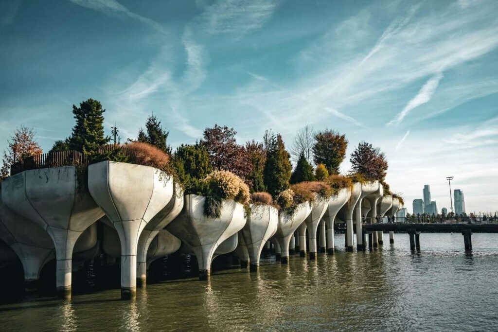 Parque flutuante Little Island no rio Hudson em Nova York com pessoas caminhando e áreas verdes, ao fundo a cidade de Manhattan.